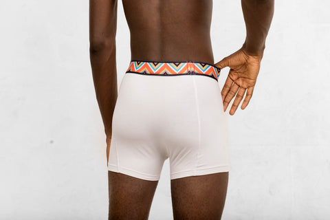 a man in white boxer briefs with a colorful belt around his waist
