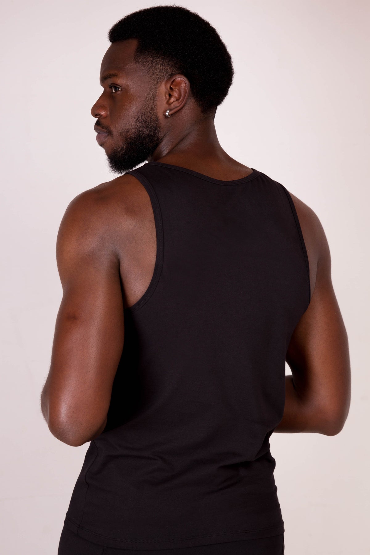 a man in a black tank top with his hands on his hips