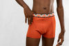 a man wearing a pair of orange trunks