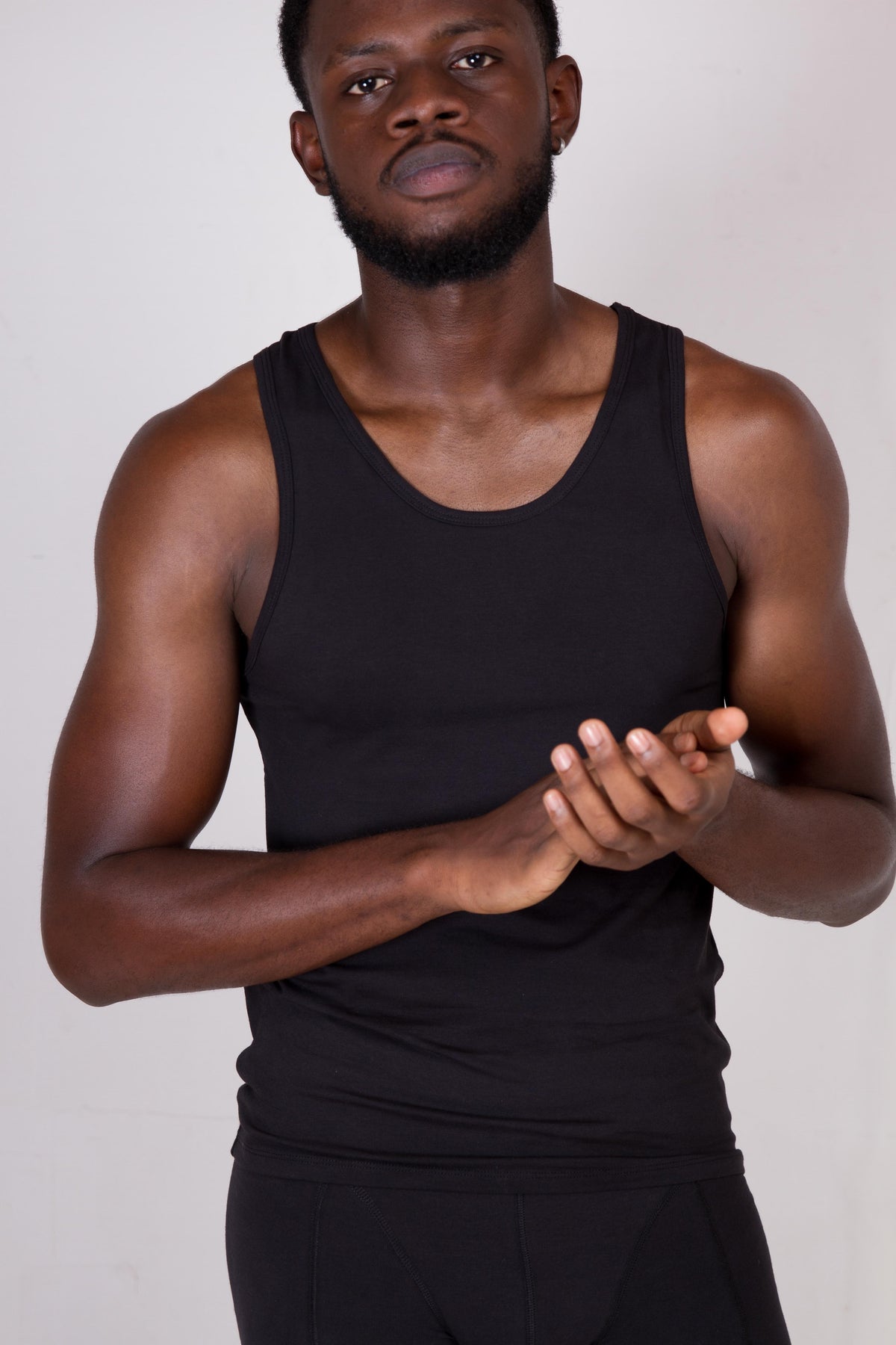 a man in a black tank top is holding his hands together